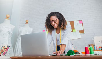 Portrait of beautiful african american black designer woman work with computer in tailer fabric fashion small business workshop office. Young owner entrepreneur creative girl textile business concept