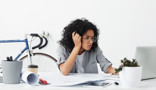 Shot of tired business enterpreneur dark-skinned female wearing big eyeglasses being worried while making her report_